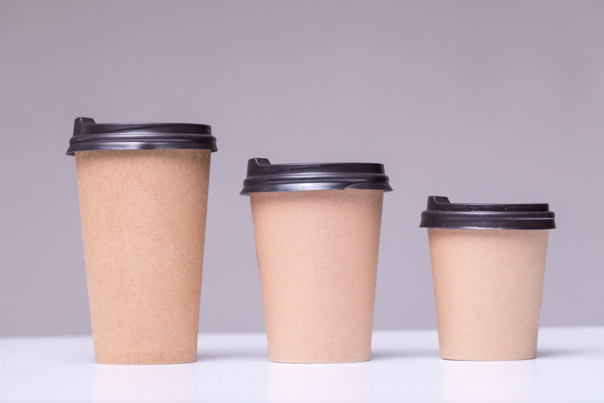 covered Paper coffee cups different sizes isolated on gray